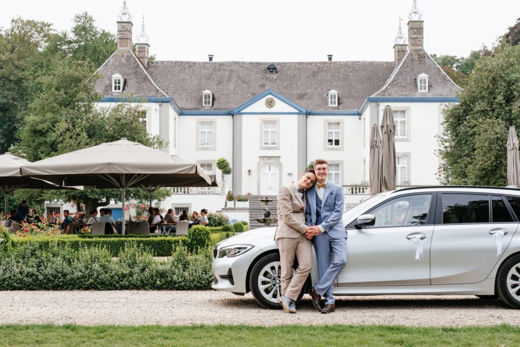 Bruidspaar voor hun BMW auto aan wijnkasteel van Genoels Elderen