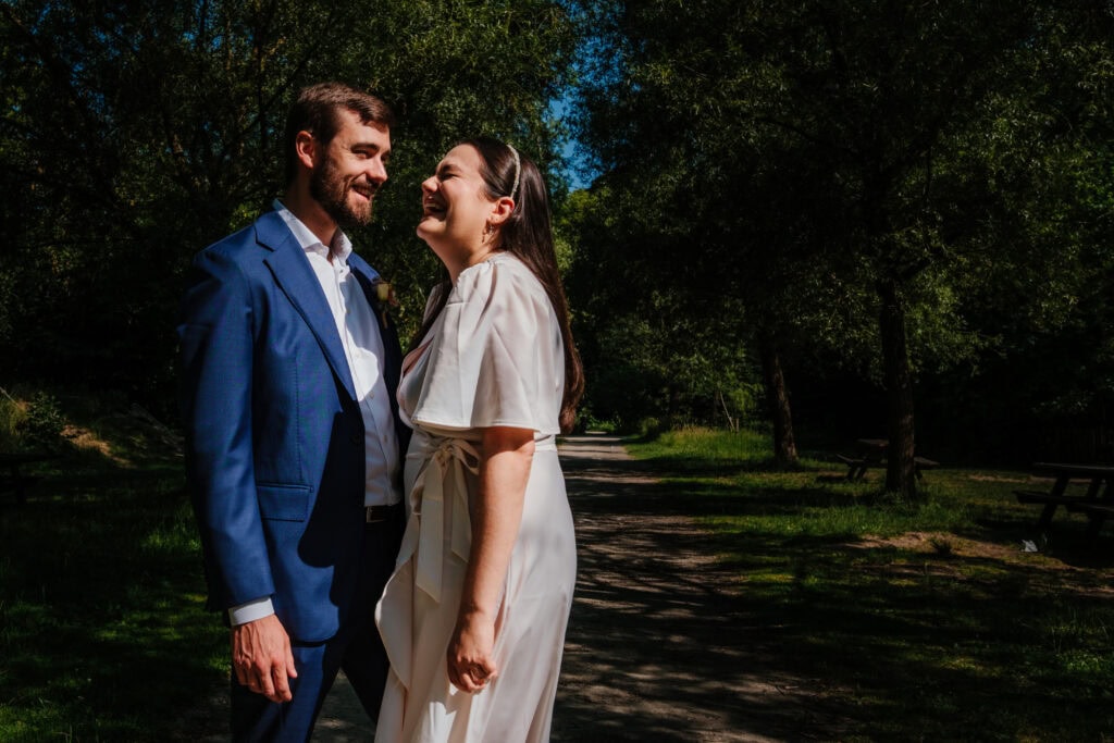 Bruidspaar bred lachend in bos vrijbroekpak